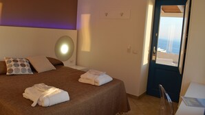 A hotel room with a bed, towels, a bedside table, and a view of the sea through a door. - A Alera Room and Breakfast (Malfa)