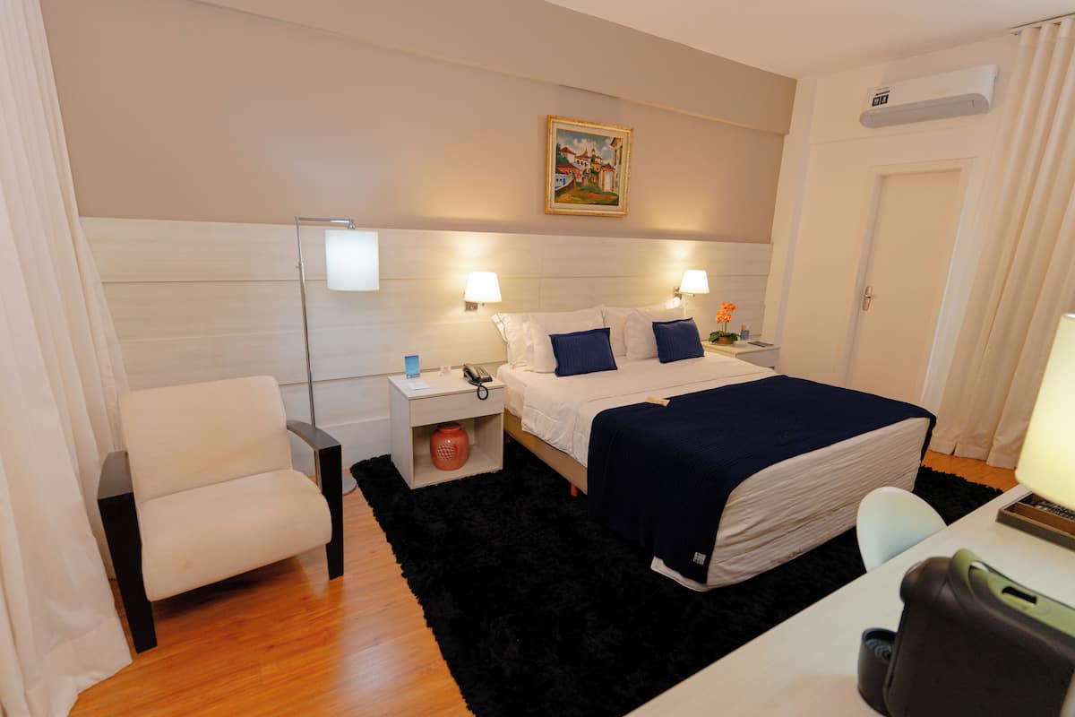 Una habitación de hotel con una cama, mesitas de noche, una silla y un escritorio.