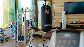 A gym with exercise equipment, a punching bag, and a TV on a wooden wall.