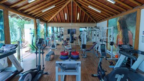 Un gimnasio con cintas de correr, elípticas y equipo de levantamiento de pesas.