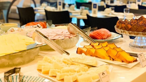 Un bufé con diversas opciones de comida, incluyendo carnes frías, frutas y pasteles.