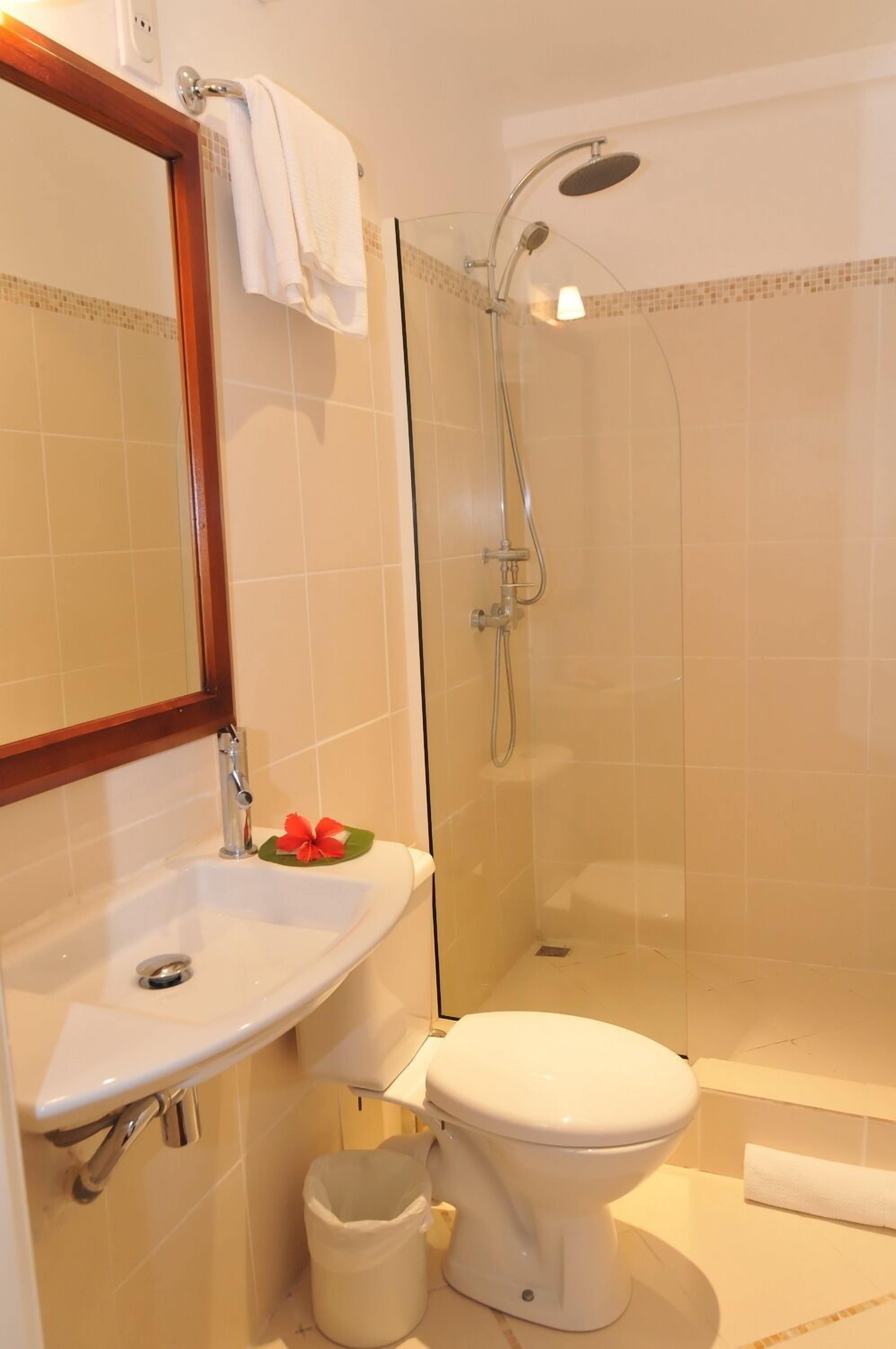 A bathroom with a sink, toilet, and glass-enclosed shower.