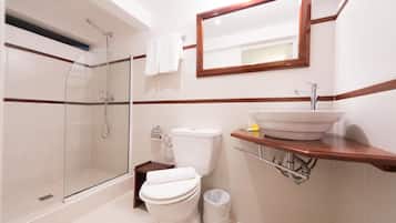 Une salle de bain moderne avec une douche à parois de verre, des toilettes blanches et un lavabo doté d’un plan de travail en bois.