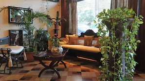 A living room with a sofa, armchairs, a coffee table, and various potted plants. - Hotel L'Imperatrice (Fort-de-France)