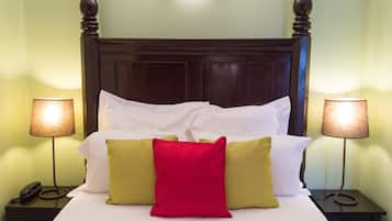 A neatly made bed with white and colorful pillows, two bedside lamps, and a wooden headboard.