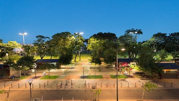 Um parque bem iluminado com caminhos, bancos e árvores.