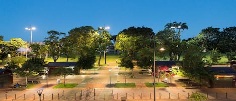 Un parque bien iluminado con senderos, bancos y árboles.
