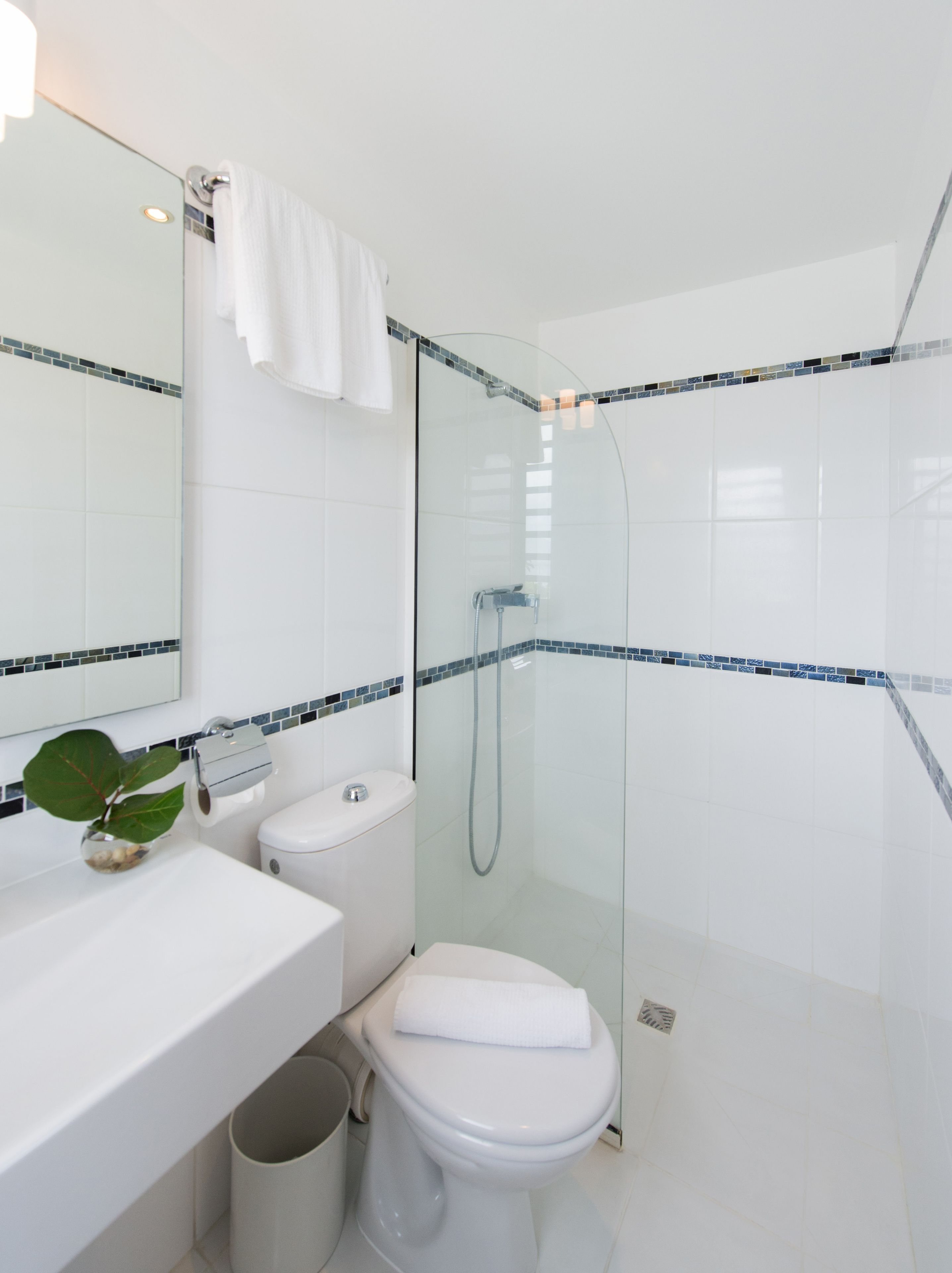 Une salle de bain moderne avec une douche à parois de verre, des accessoires blancs et un mur recouvert de carreaux.