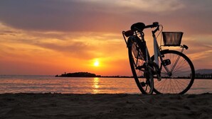 Een fiets met mandje op het strand bij zonsondergang.