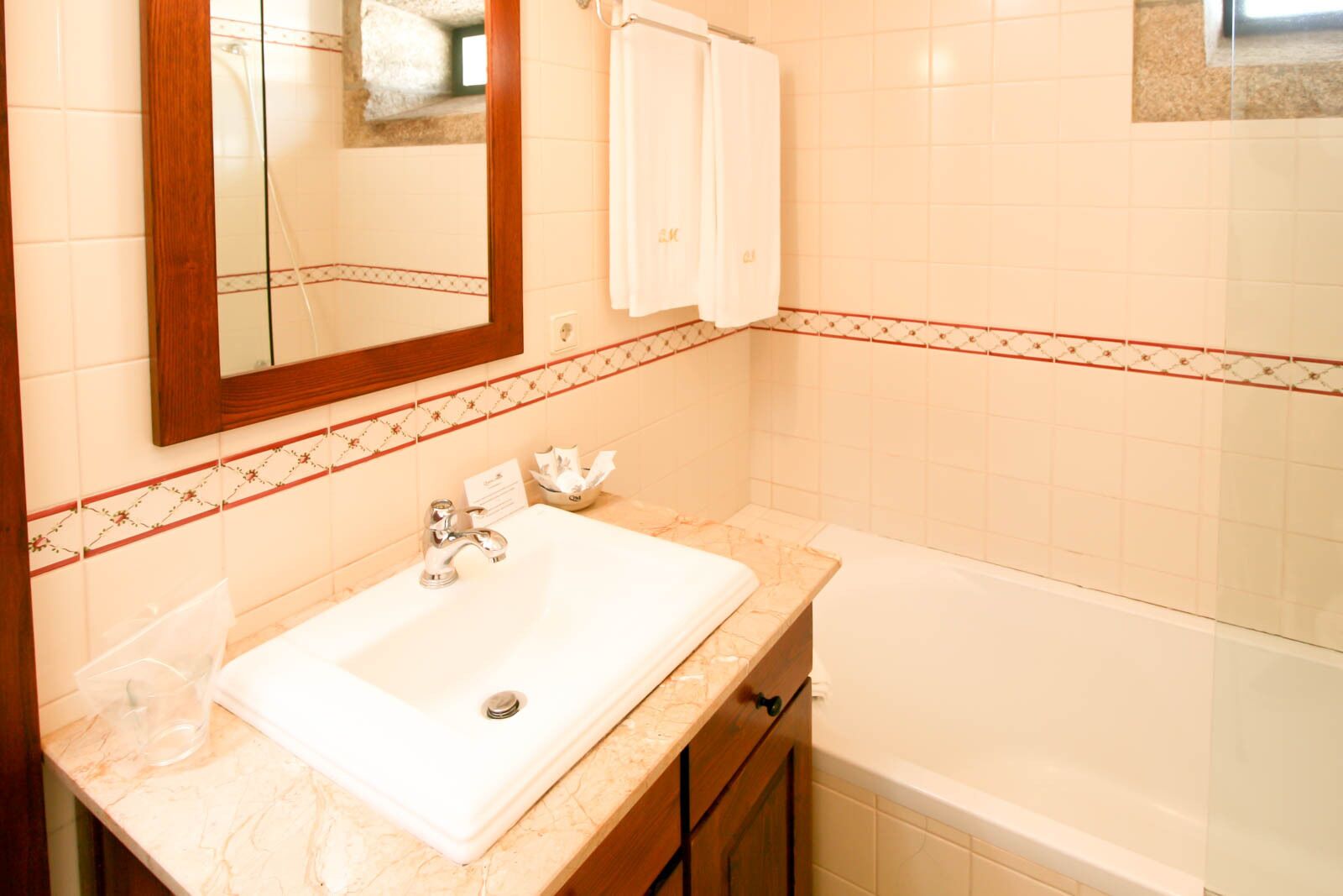 Un bagno con un lavandino bianco, uno specchio e una vasca.