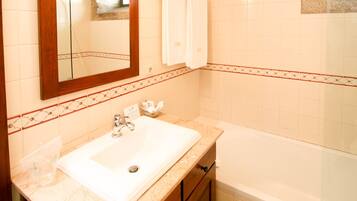 Un bagno con un lavandino bianco, uno specchio e una vasca.