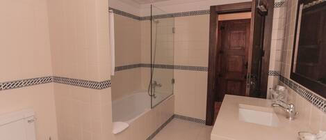 Een badkamer met een bad, toilet, wastafel en spiegel.