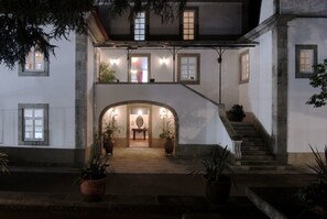 A two-story building with a central archway leading to a staircase. - Quinta de Malta (Barcelos)