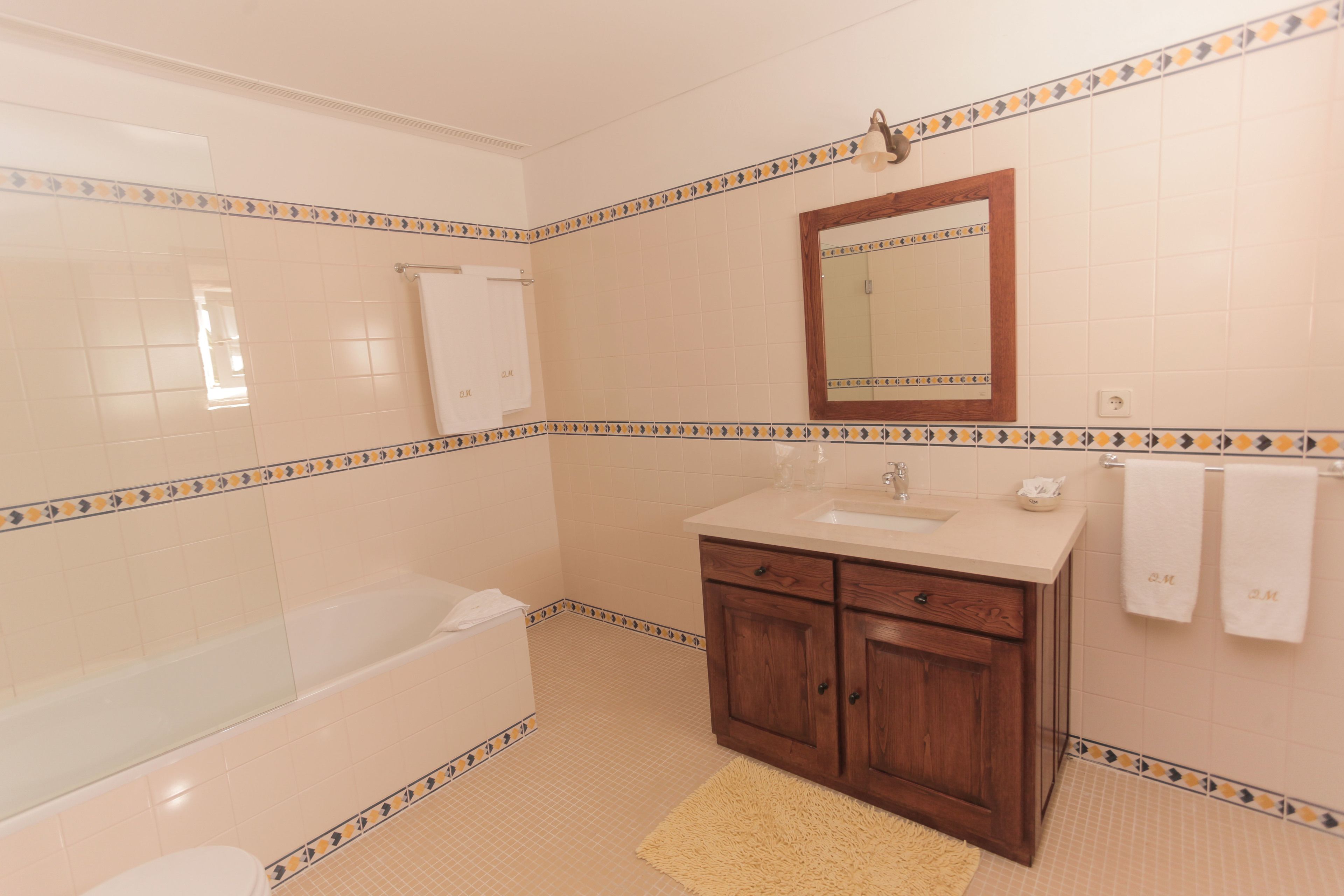 Une salle de bain avec une baignoire, un lavabo, un miroir et des meubles en bois.