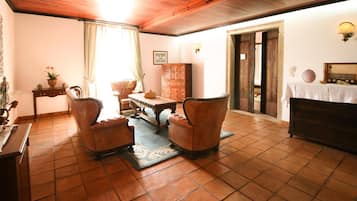 A traditional living room with a wooden ceiling, a fireplace, a sofa set, a coffee table, and a cabinet.