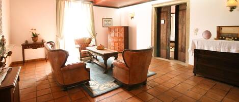 A traditional living room with a wooden ceiling, a fireplace, a sofa set, a coffee table, and a cabinet.