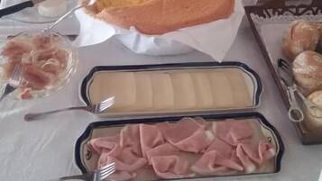 Una mesa de buffet con diversos alimentos, incluyendo un pastel grande, frutas y carnes.