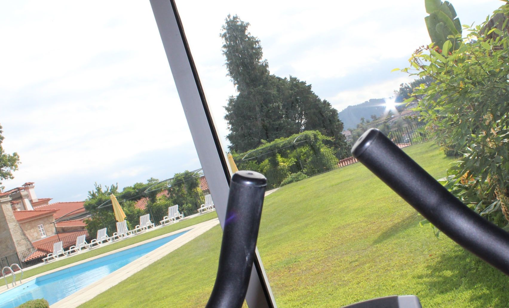 Une vue depuis une fenêtre donnant sur une piscine, avec des chaises longues et une pelouse.