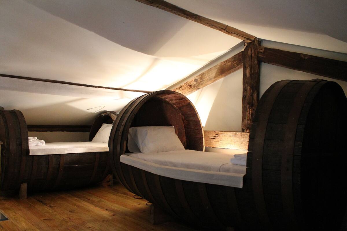 Een kamer met twee bedden in houten vaten, een houten plafond en een houten vloer.