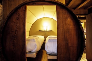 A wooden barrel-shaped room with a bed and a lamp. - Quinta do Rapozinho (Cabeceiras de Basto)