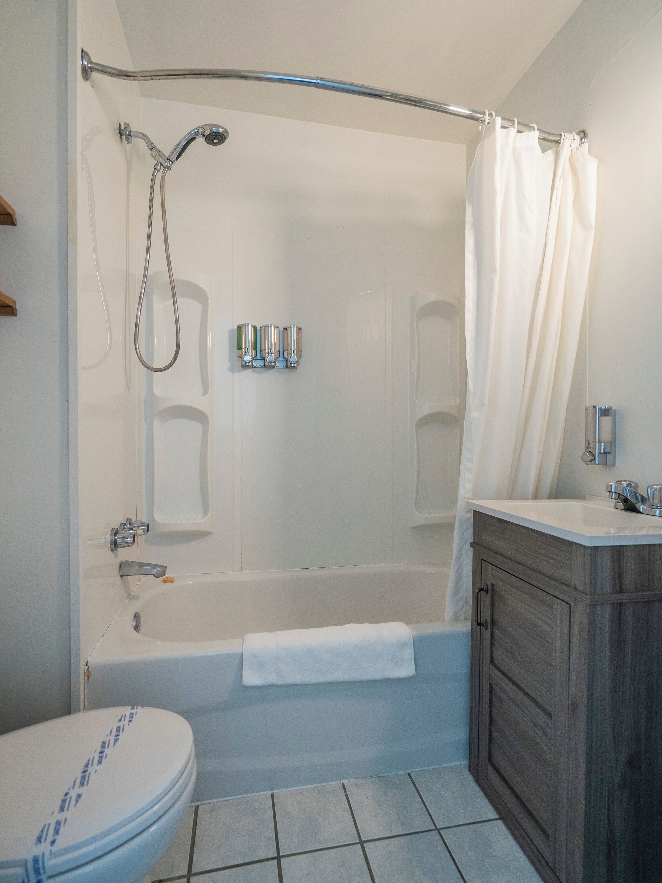 A bathroom with a bathtub, toilet, and a shower area.