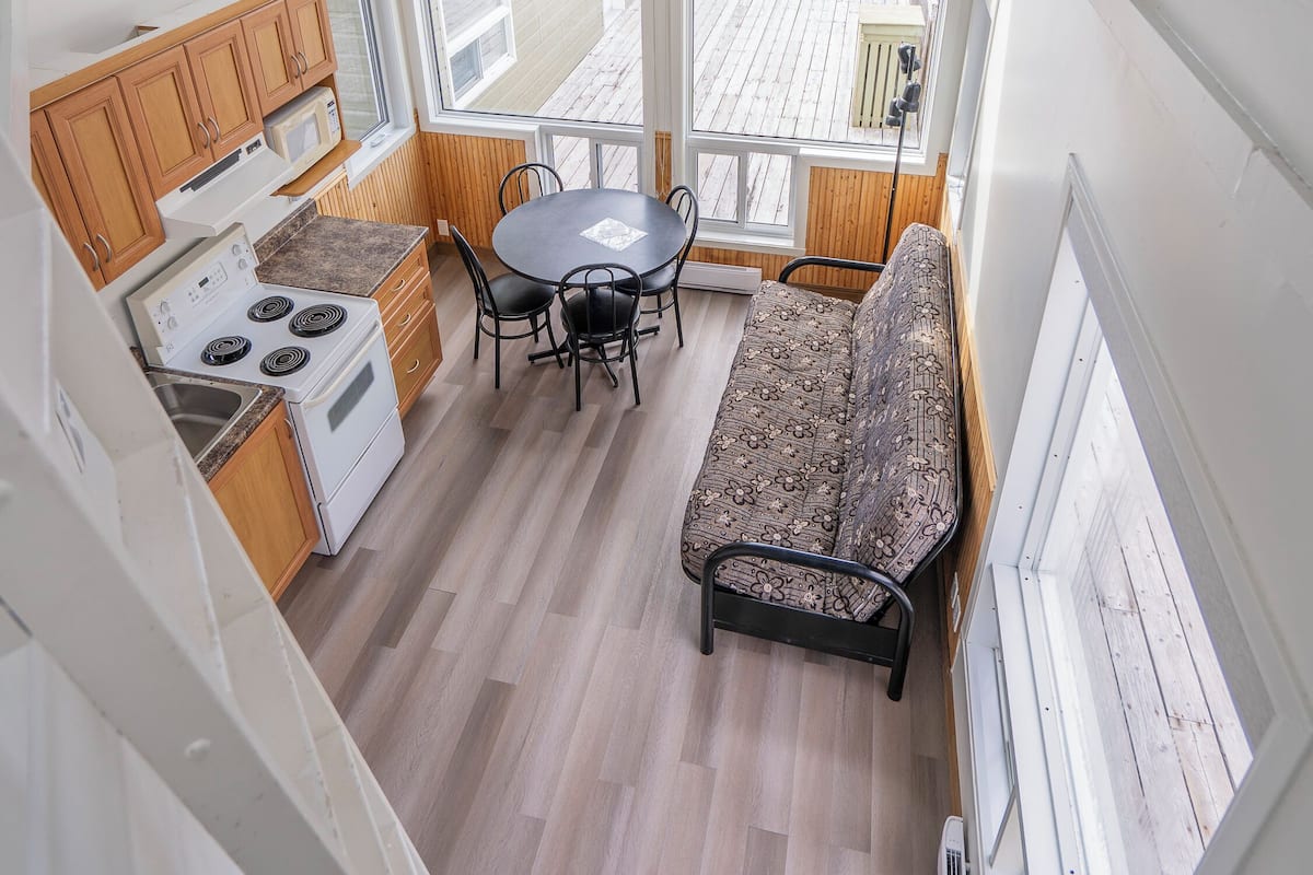 A compact kitchen with a dining area, a built-in oven, and a window overlooking a wooden deck.
