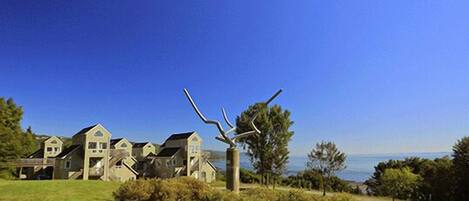 A residential area with multiple houses, a sculpture, and a view of the sea.