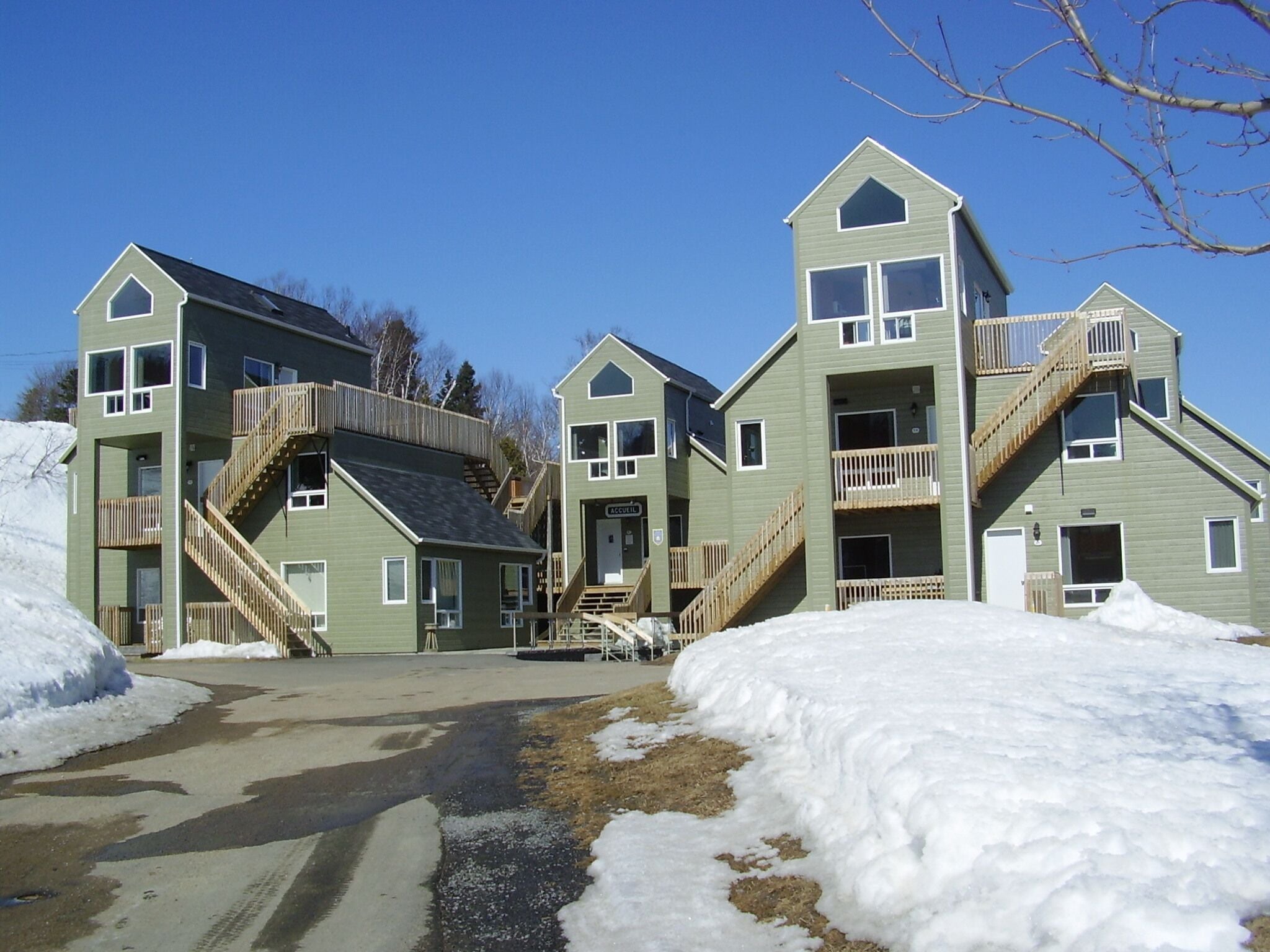 A row of multi-story buildings with external wooden staircases and balconies, surrounded by snow.