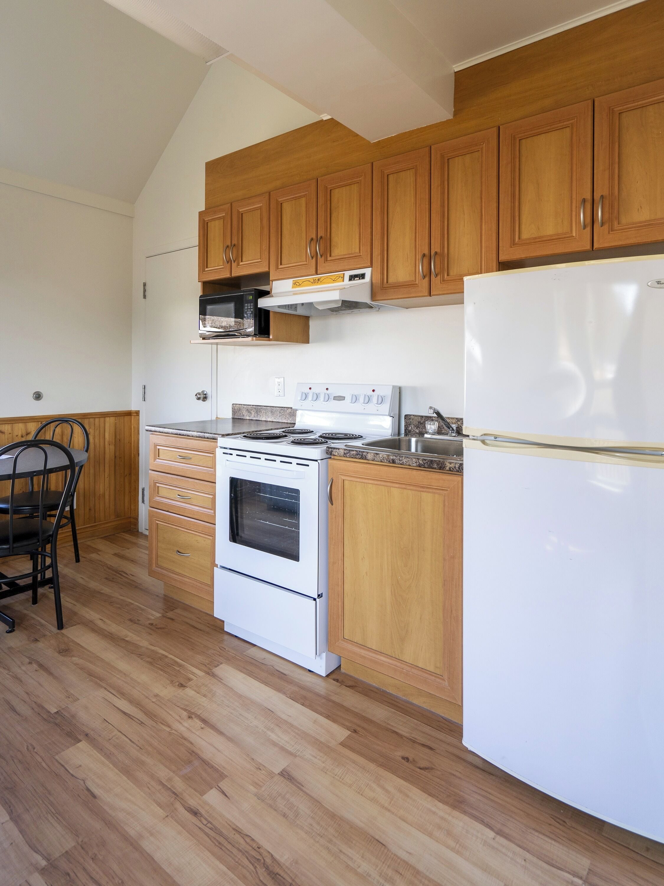 A kitchen with wooden cabinets, a white stove, and a refrigerator.