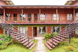 A two-story wooden building with a balcony and a central staircase leading to the entrance. - Pensión Santa Elena (Monteverde)