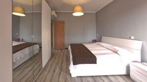 A modern hotel room with a large bed, bedside tables, a wardrobe, and a mirror. - Residence Riviera (Pietra Ligure)