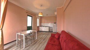 A compact living space with a dining area, kitchenette, and a red sofa. - Residence Riviera (Pietra Ligure)