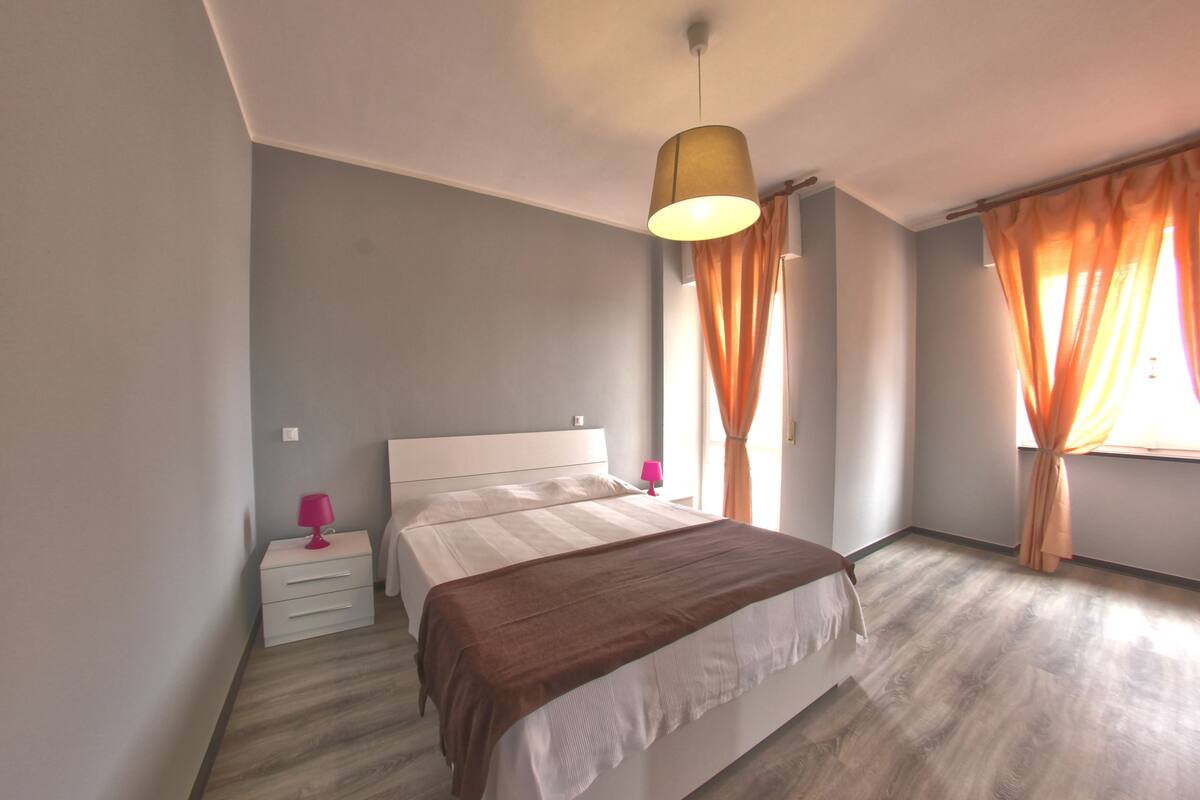 A bedroom with a bed, bedside tables, a lamp, and curtains.