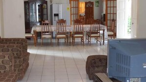 Un comedor con una mesa, sillas, ventilador de techo y televisor.