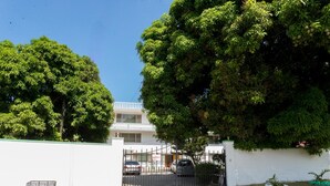 Un residencial cerrado con un edificio blanco, un árbol grande y un camino de entrada pavimentado.