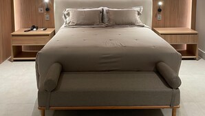 A modern bedroom with a large bed, wooden headboard, bedside tables, and recessed lighting. - Paiaguás Palace Hotel (Cuiabá)
