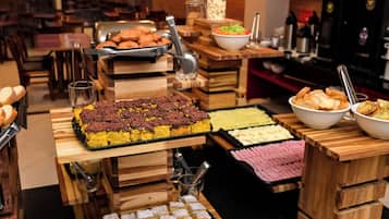 Un bufé con diversos postres y aperitivos, incluyendo pasteles y productos de repostería, dispuestos sobre puestos de madera.