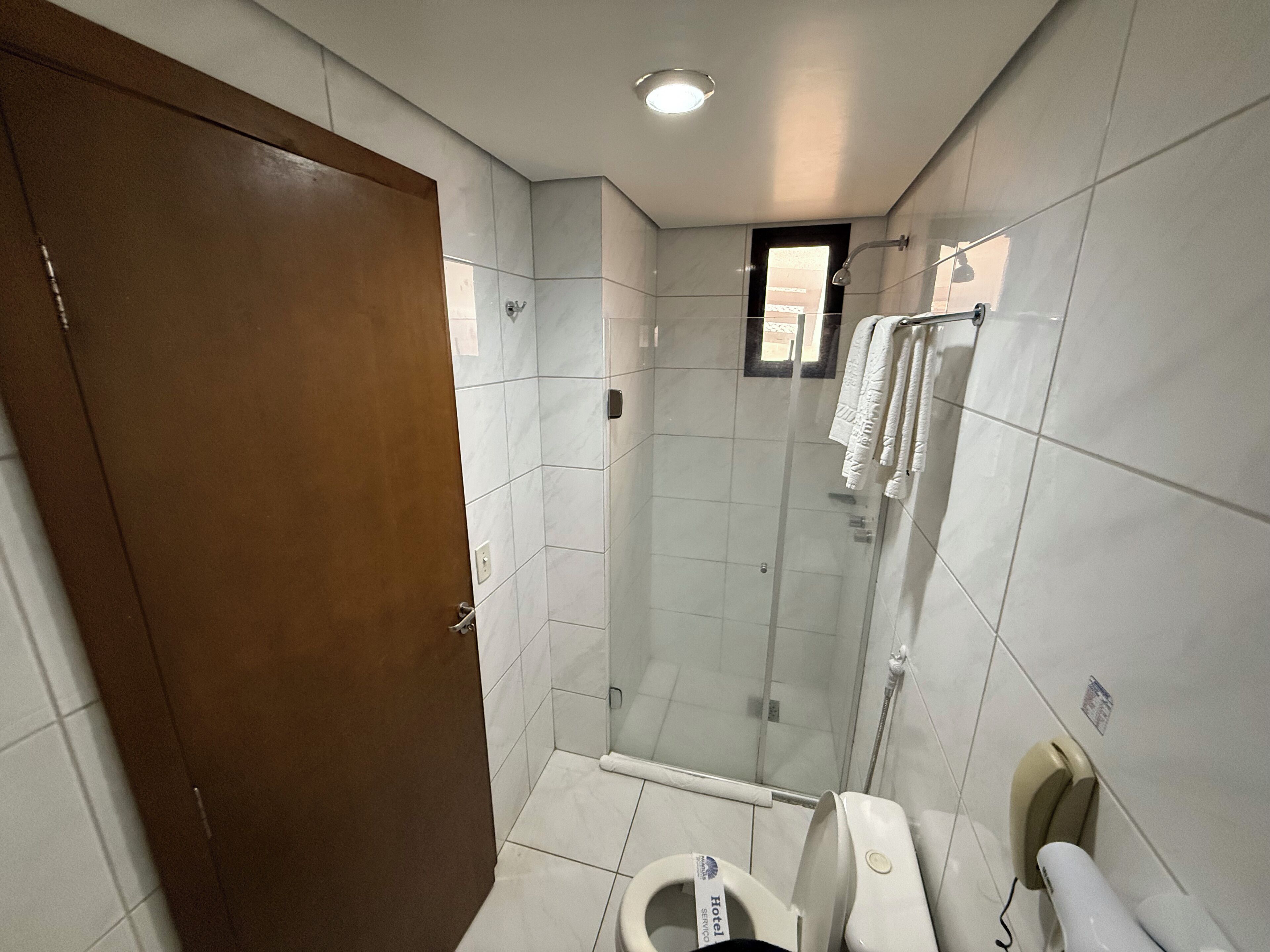 Een hotelbadkamer met douche, toilet en handdoekrek.