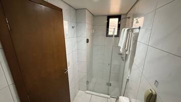 A hotel bathroom with a shower, toilet, and towel rack.