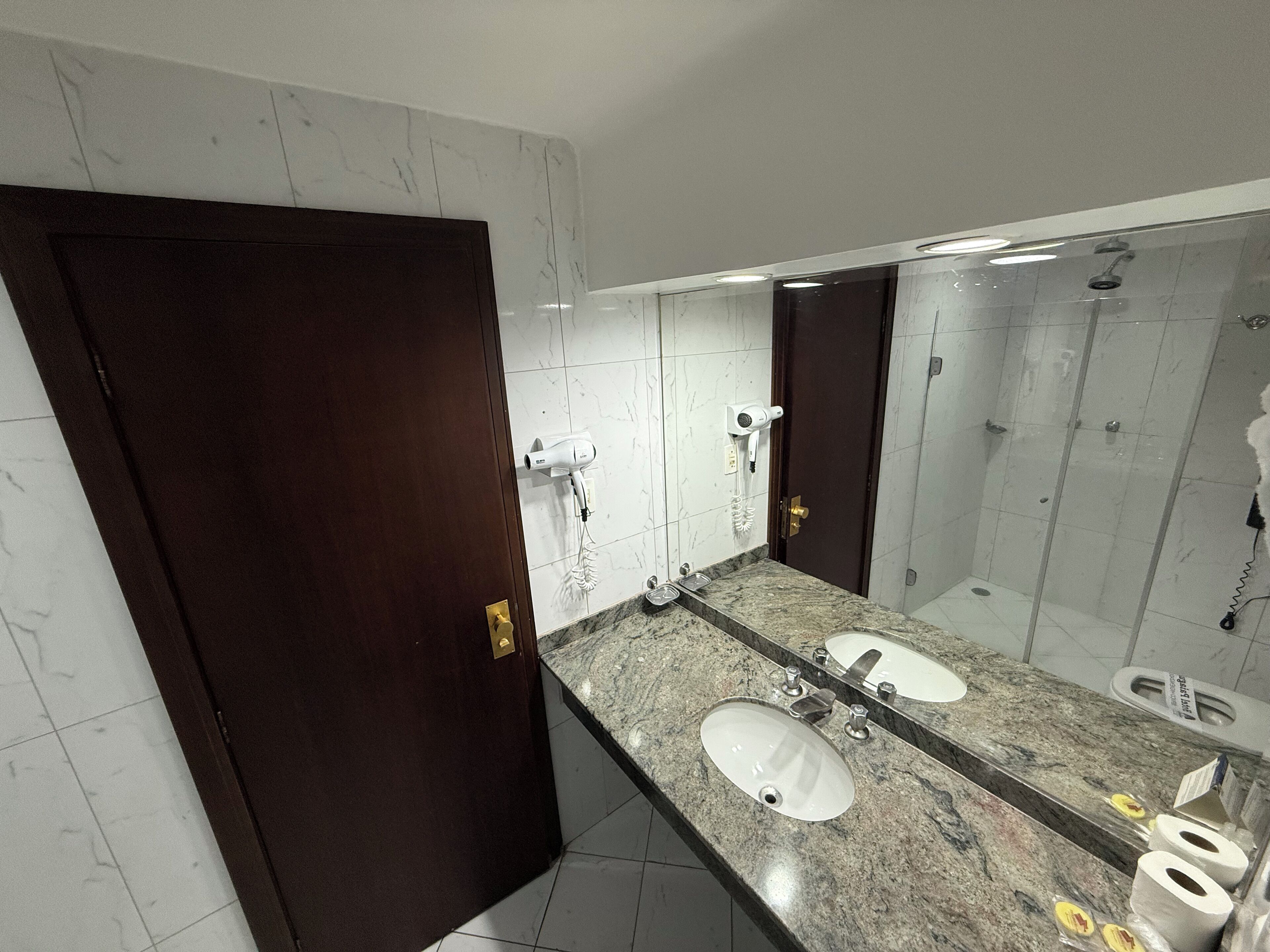 A bathroom with two sinks, a large mirror, and a shower area.