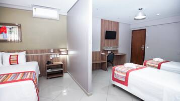 Quarto de hotel com duas camas, uma mesa, uma televisão e um guarda-roupa.