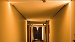 A hotel corridor with a central carpeted walkway, flanked by walls and doors, and illuminated by linear ceiling lights. - Paiaguás Palace Hotel (Cuiabá)