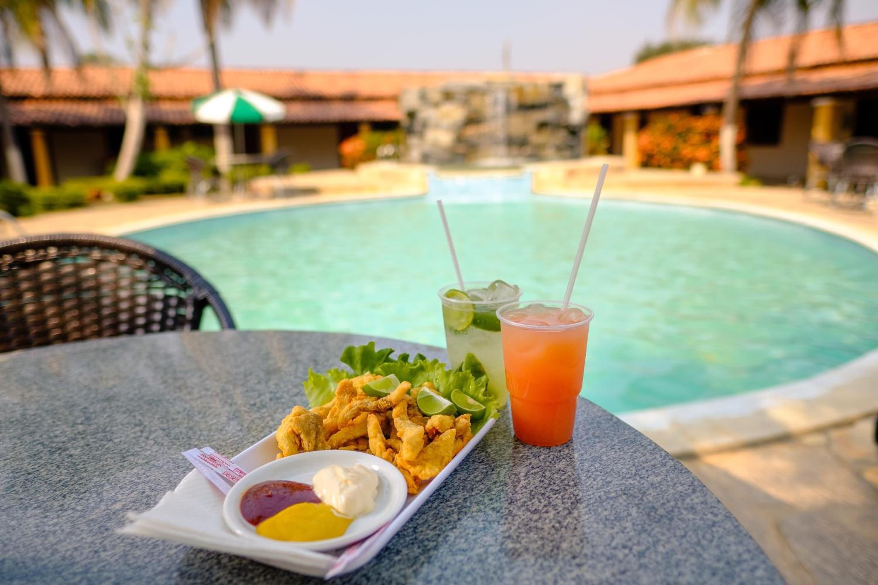 Une table avec une assiette de nourriture frite, une boisson et des condiments.