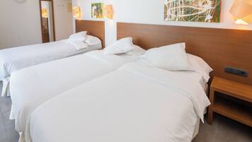 Une chambre d’hôtel avec deux lits, une tête de lit en bois, une table de chevet et des œuvres d’art accrochées au mur.