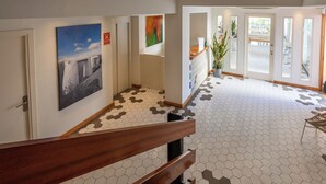 A hotel lobby with a staircase, hexagonal patterned floor, artwork on the walls, and a reception desk. - Hotel Es Mitjorn (Sant Antoni de Portmany)
