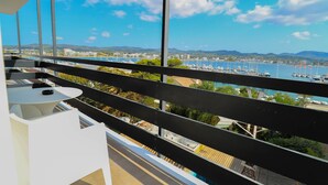 A balcony with a view of a marina and distant mountains. - Hotel Es Mitjorn (Sant Antoni de Portmany)