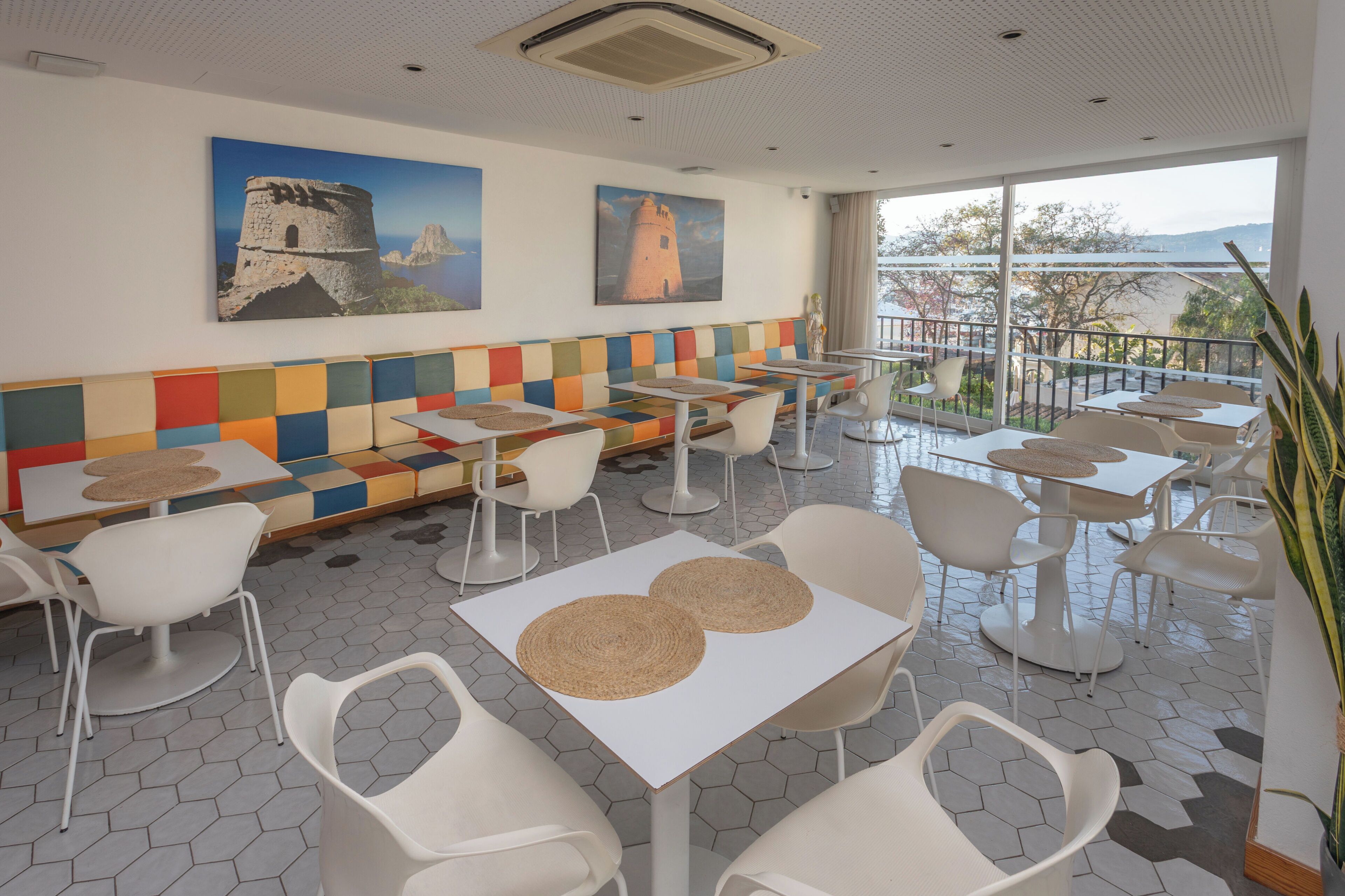 Un restaurante con una pared colorida, mesas y sillas blancas y pinturas de faros.