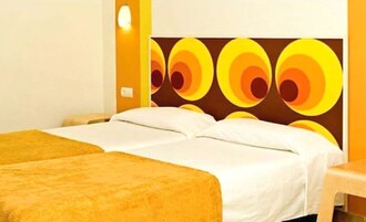 Una habitación de hotel con dos camas, un mural grande en la pared y una mesita pequeña.