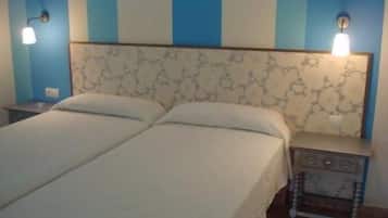 A double bed with a patterned headboard, bedside tables with lamps, and a blue and white striped wall.