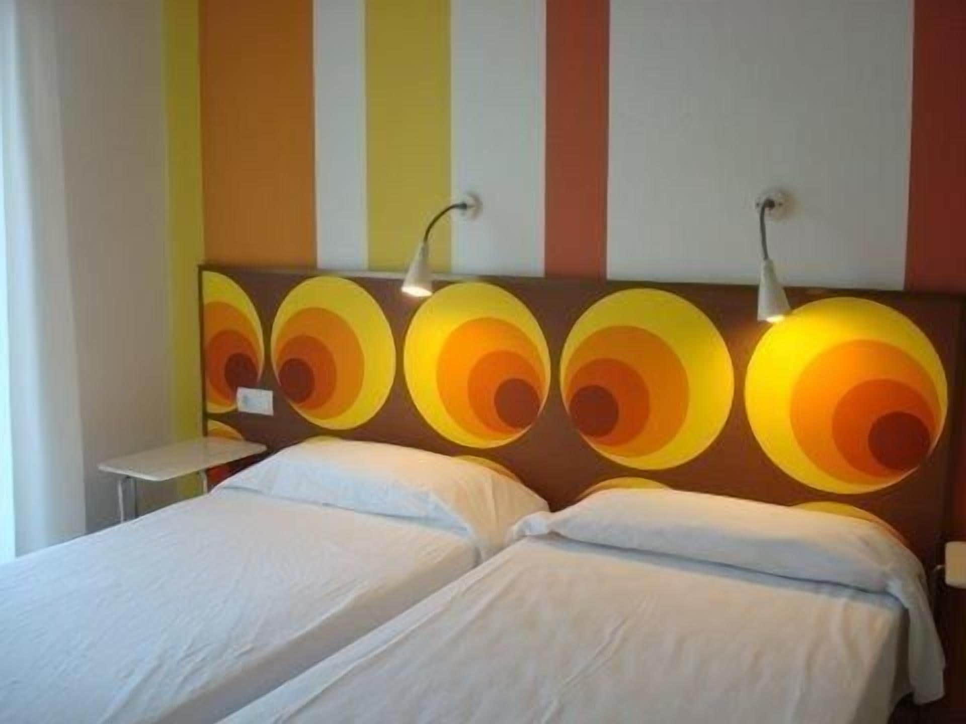 Une chambre d’hôtel avec un lit, une table de chevet et un mur orné d’appliques murales rondes.
